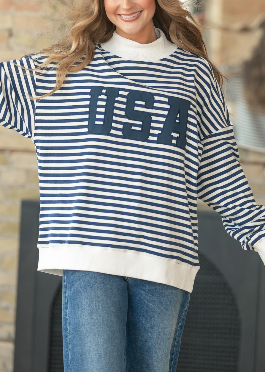 Close-up of navy USA applique lettering on striped mockneck sweatshirt