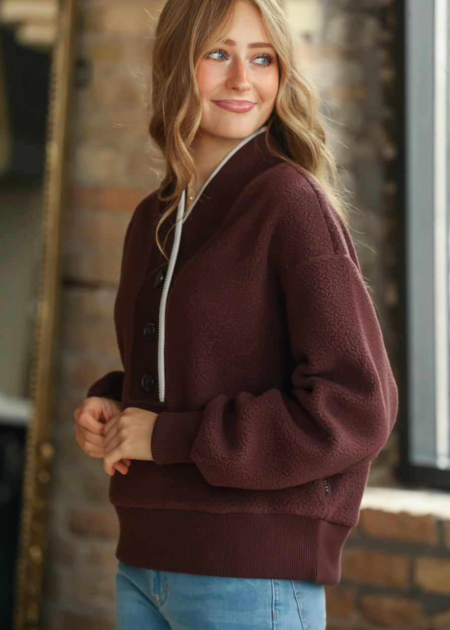 Side view of Mahogany fleece pullover showing relaxed sleeves, button neckline, and hip-length fit.