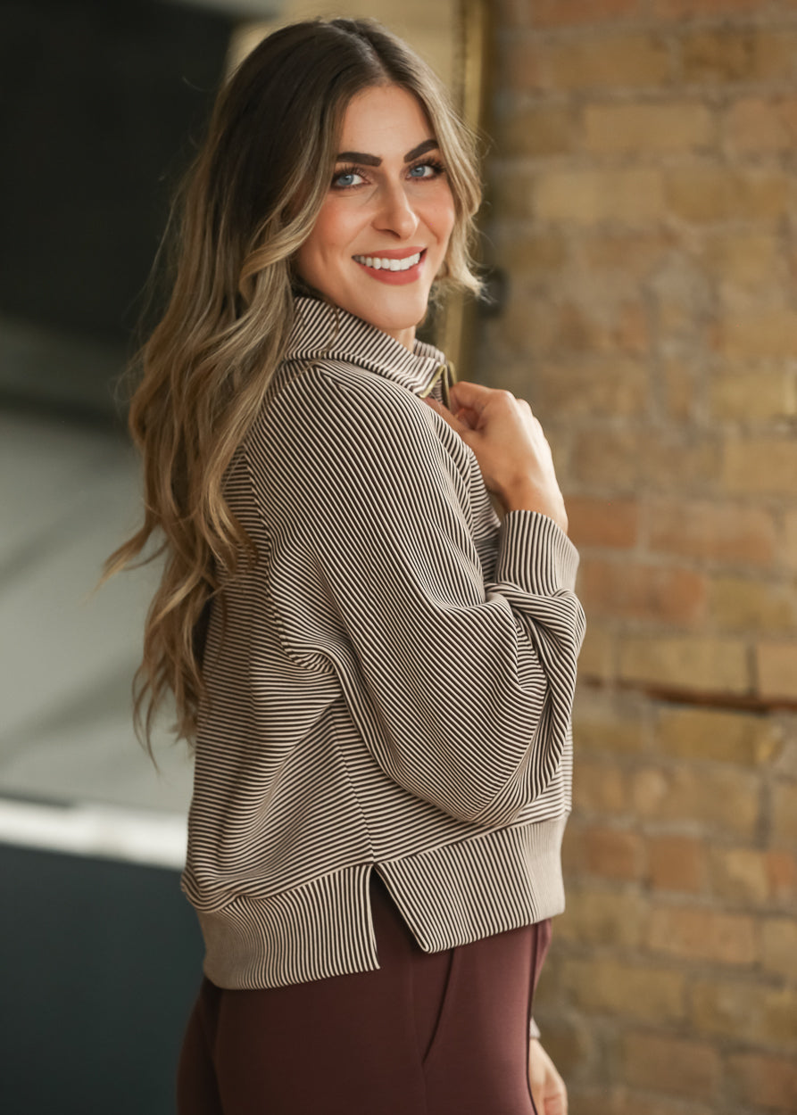 Side view of striped half zip pullover showing the hip-length hem and loose silhouette.