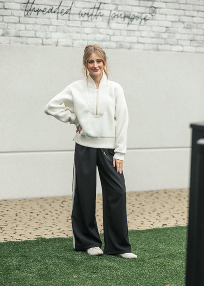 Front view of cream half zip fleece styled with black wide-leg pants