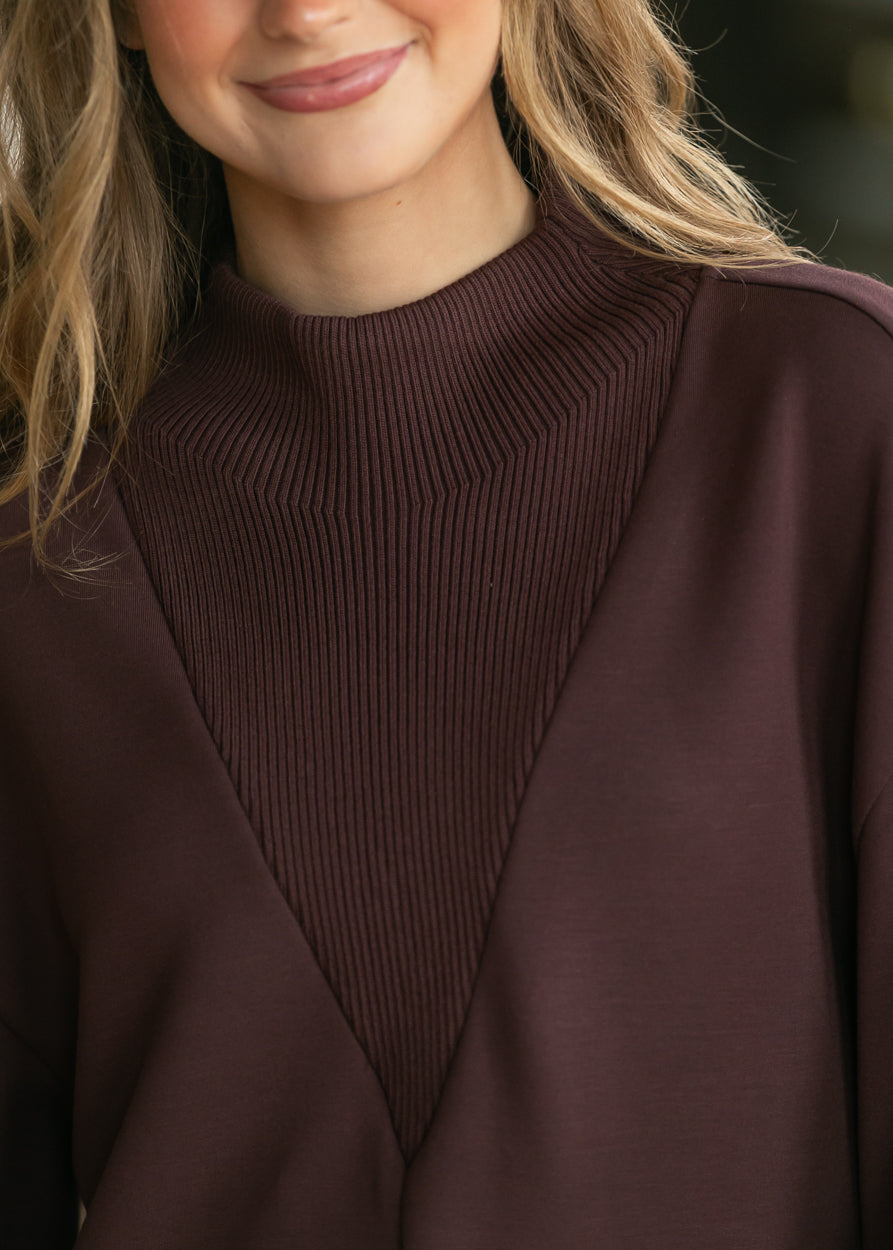 Close-up of chocolate brown Varley Novi sweatshirt with ribbed mock neck and V-shaped ribbed front panel.