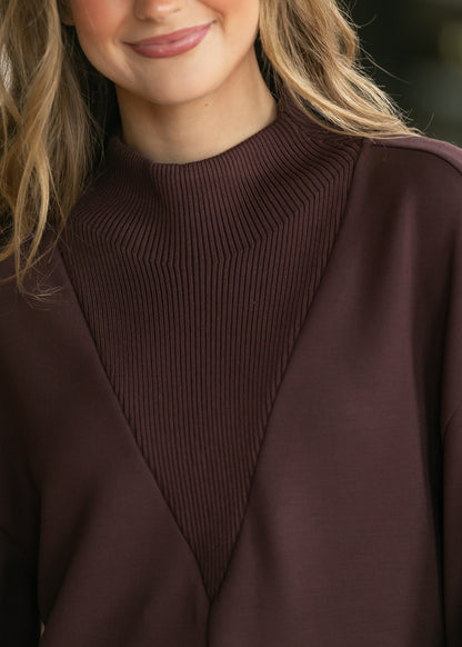 Close-up of chocolate brown Varley Novi sweatshirt with ribbed mock neck and V-shaped ribbed front panel.