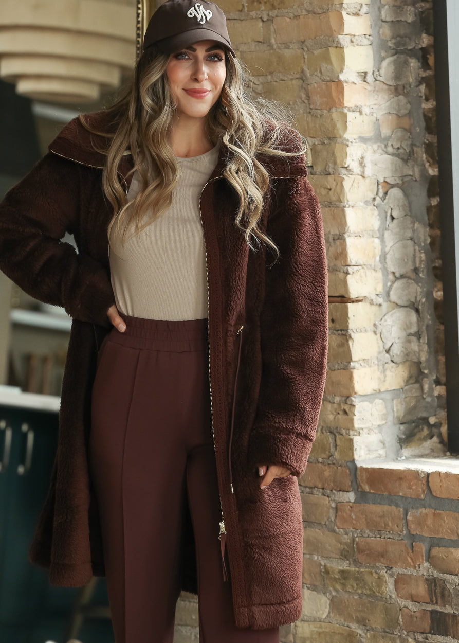 Brown Varley Melvin Club Cap with white embroidered logo styled with a burgundy sherpa coat.