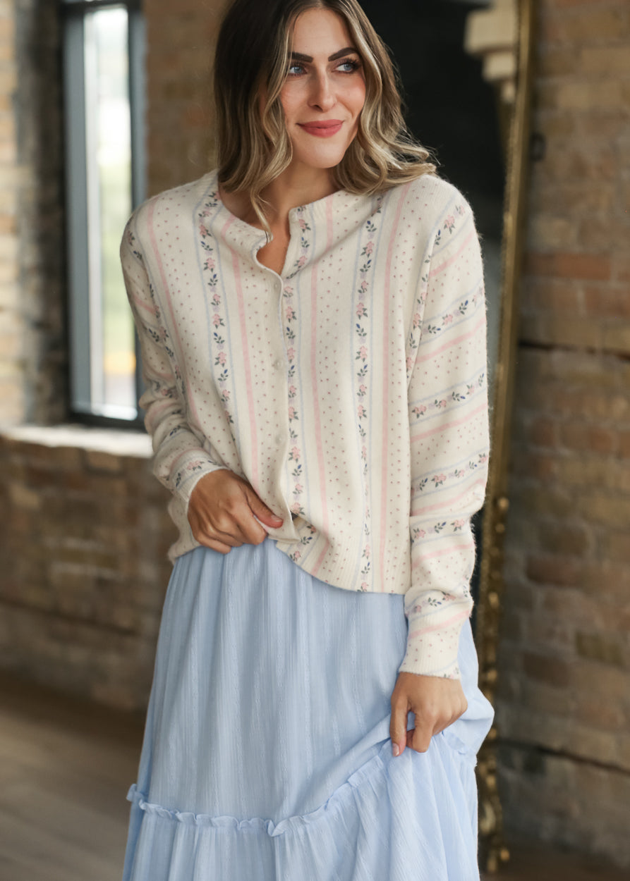 Cream floral stripe knit cardigan with pink and blue details, long sleeves, and functional buttons.