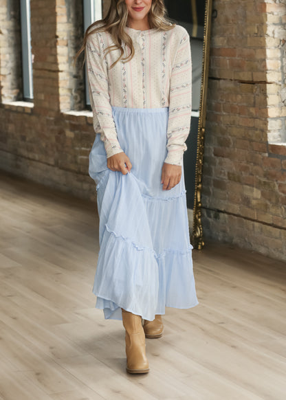 Cream button-front knit cardigan styled with a light blue maxi skirt and neutral boots.