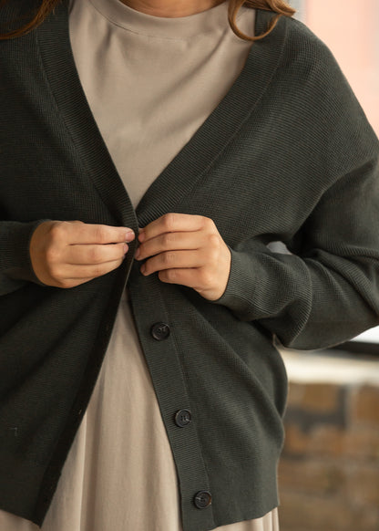 Dark olive knit cardigan styled open over a taupe midi dress