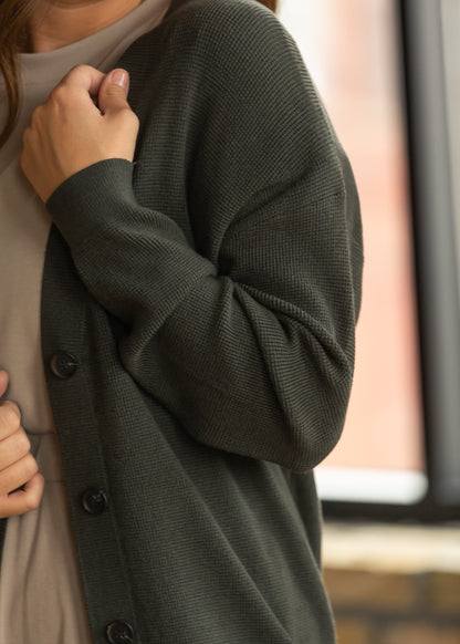 Dark olive cardigan with loose fit styled with a neutral midi dress and boots