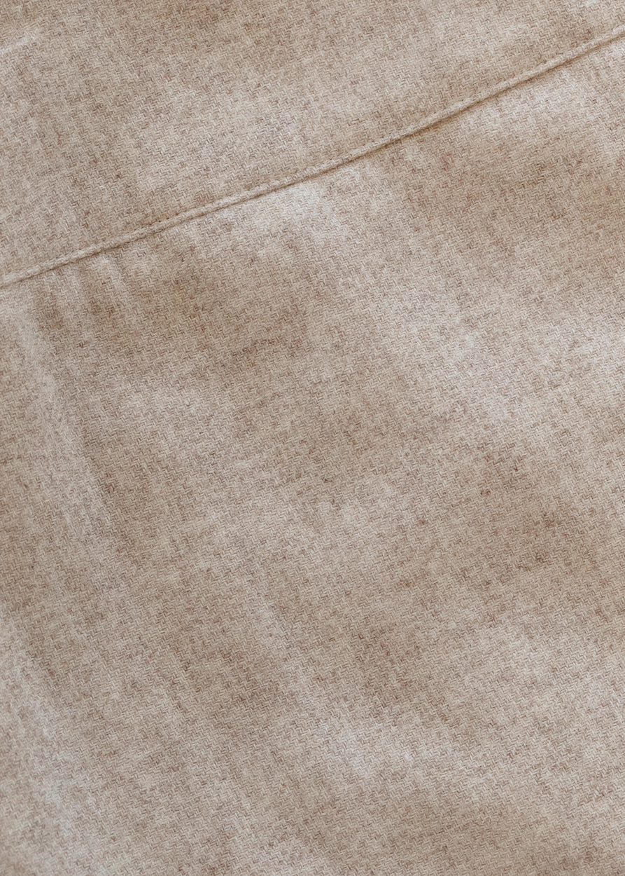 Close-up of the wide waistband and tailored front of the Wanda oatmeal wool midi pencil skirt.
