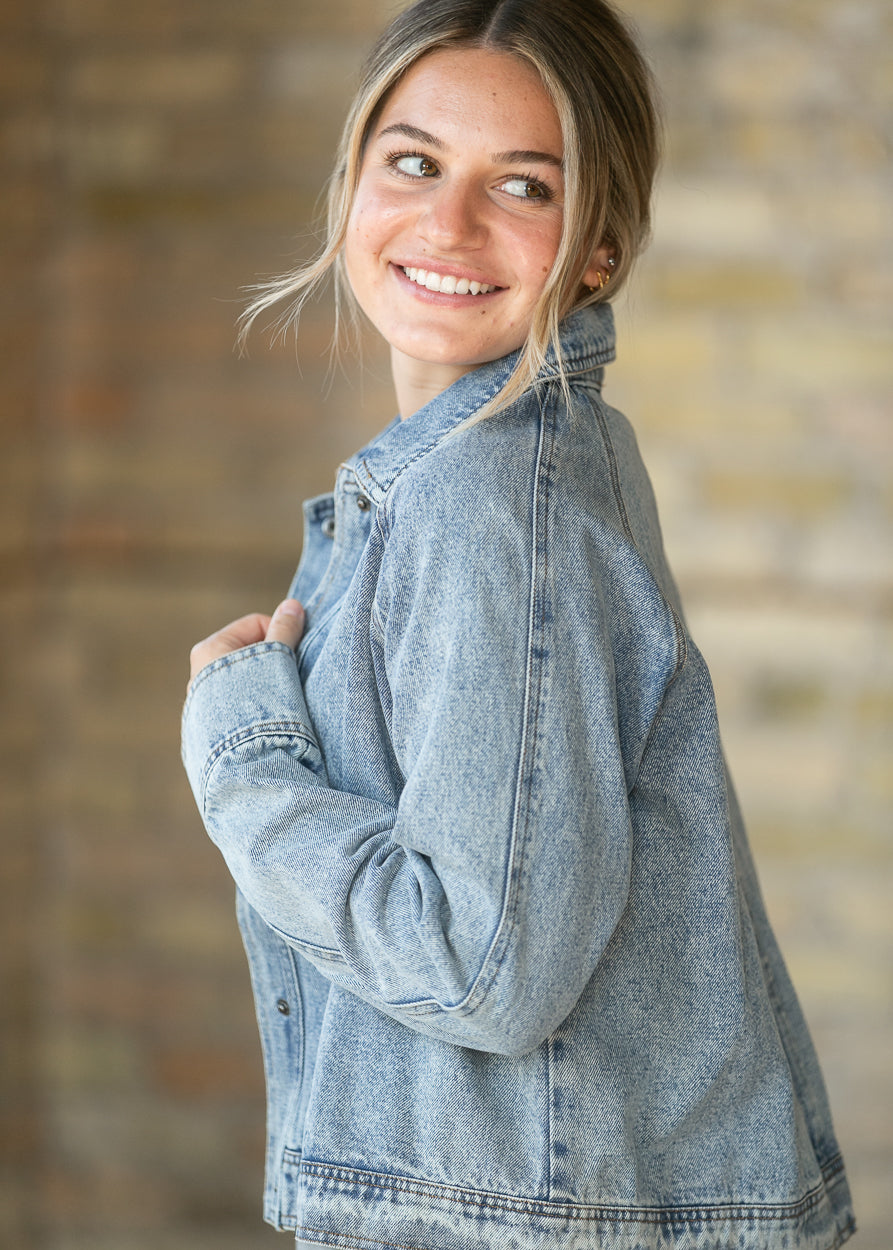 Light wash denim jacket shown from the side with relaxed sleeves and cropped hem.