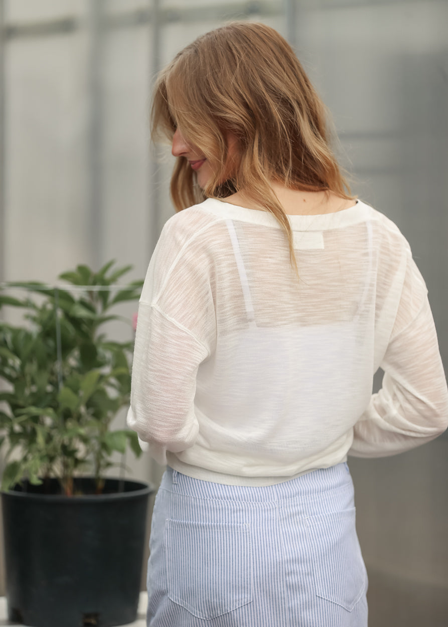 Back detail of white cardigan layered over a blue striped midi skirt