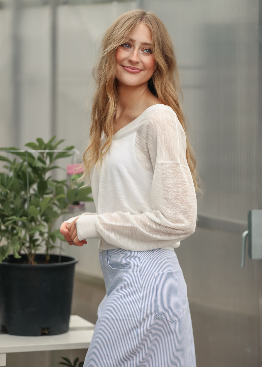White sheer knit cardigan styled with a light blue striped midi skirt