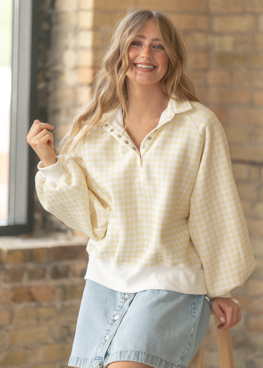 Yellow gingham quarter snap pullover with collared neckline and oversized fit styled with a light denim skirt.