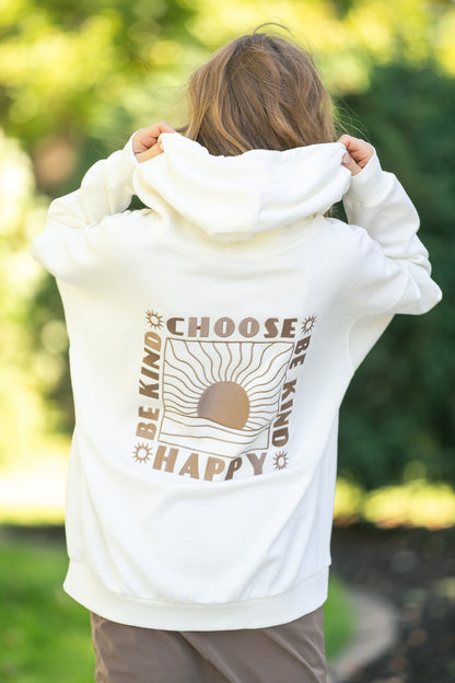 Person wearing a white hoodie with 'Be Kind Choose Happy' text on the back, standing outdoors.