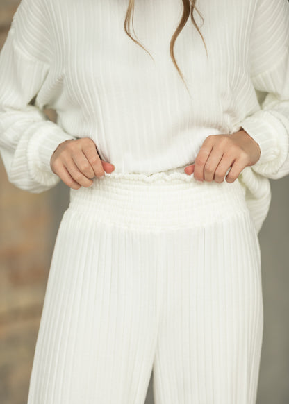 Close-up of bone white ribbed pants showing stretchy smocked waistband and vertical texture.
