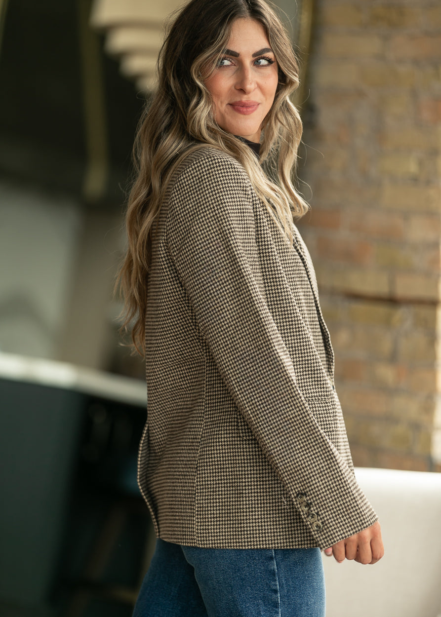 Side view of tan and black check blazer showing notched lapel and button-detail cuff.