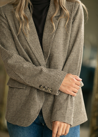 Close-up of tan and black check blazer showing single-button front, notched lapel, and flap pocket.