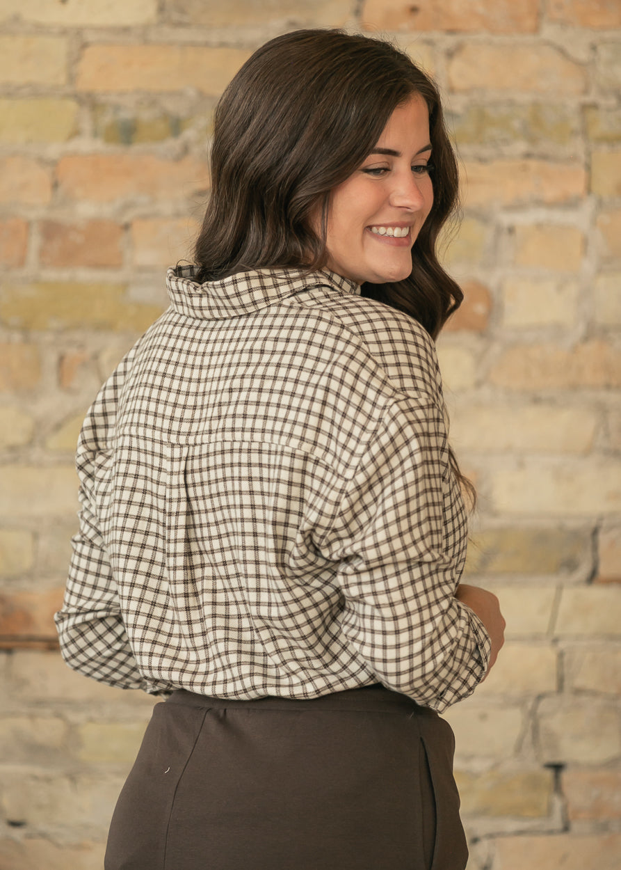Close-up back view of cream and chocolate plaid button-up top showing the plaid pattern and loose drape.