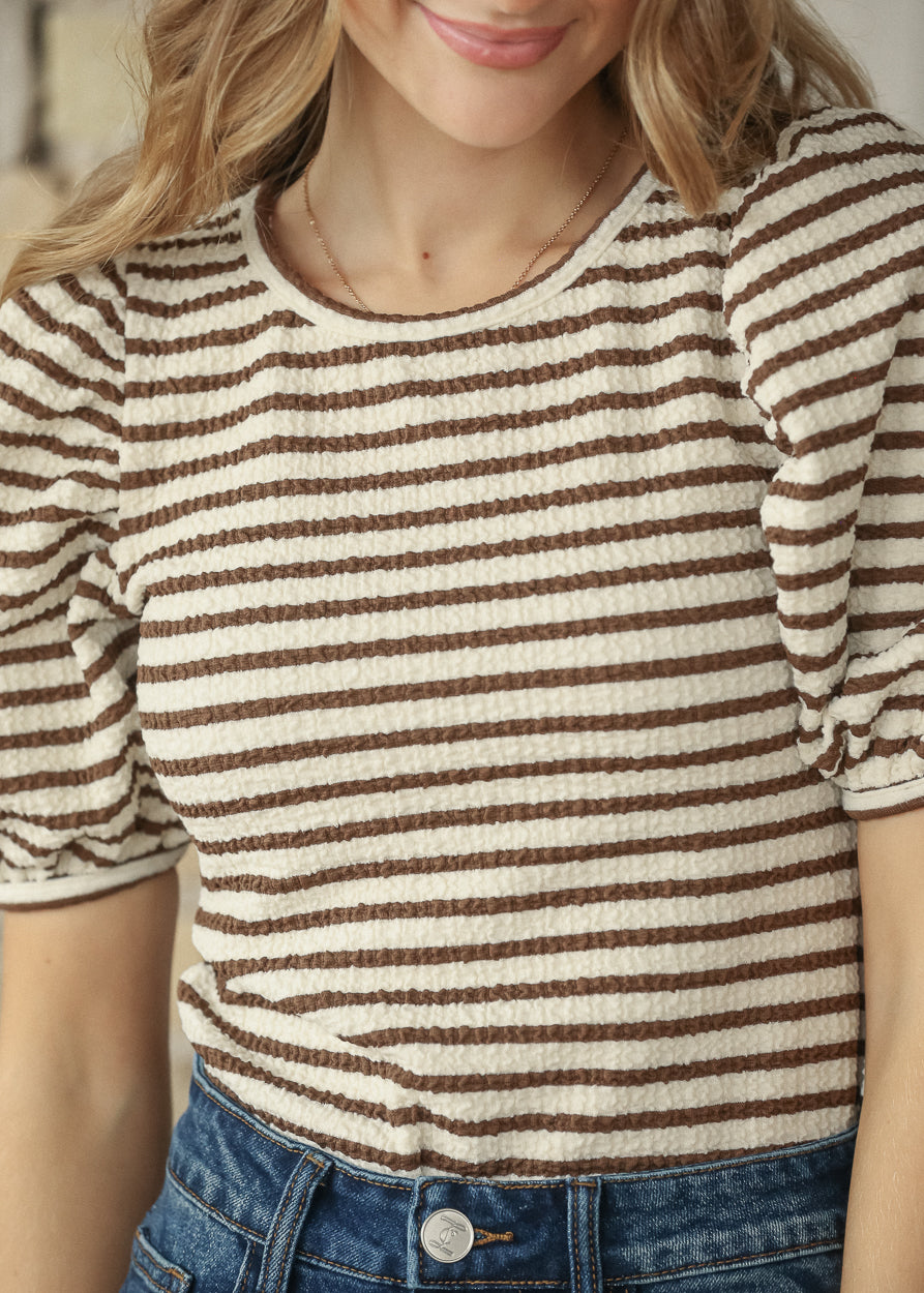 Close-up of brown striped short sleeve tee showing crew neckline and relaxed fit.
