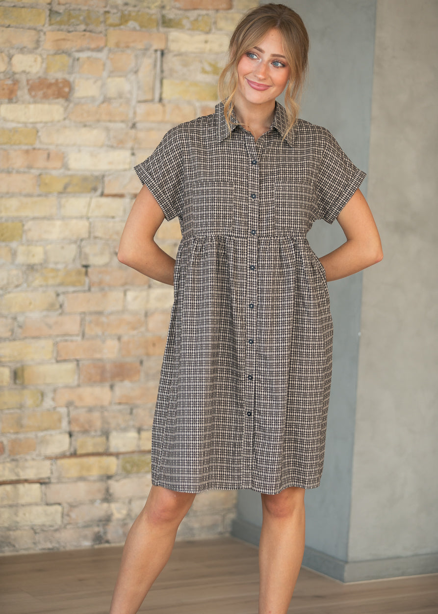 Close-up of brown plaid Zuri dress with collar, button-front detail, and two chest pockets.