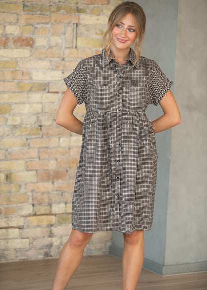 Close-up of brown plaid Zuri dress with collar, button-front detail, and two chest pockets.