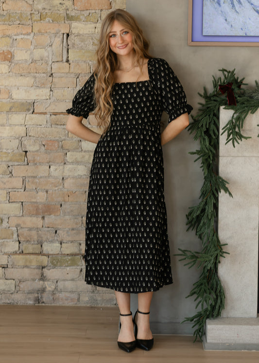 Black midi dress with small cream floral motifs, a square neckline, and gently gathered skirt.