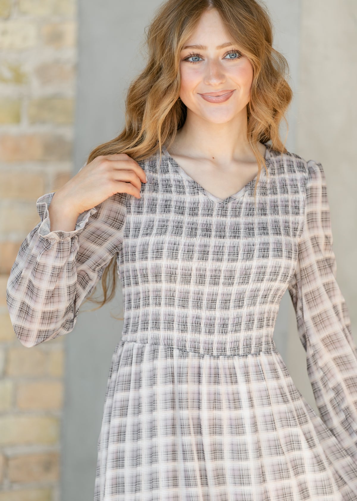 Close-up of the smocked V-neckline and ruffled cuff detail on the taupe plaid maxi dress.
