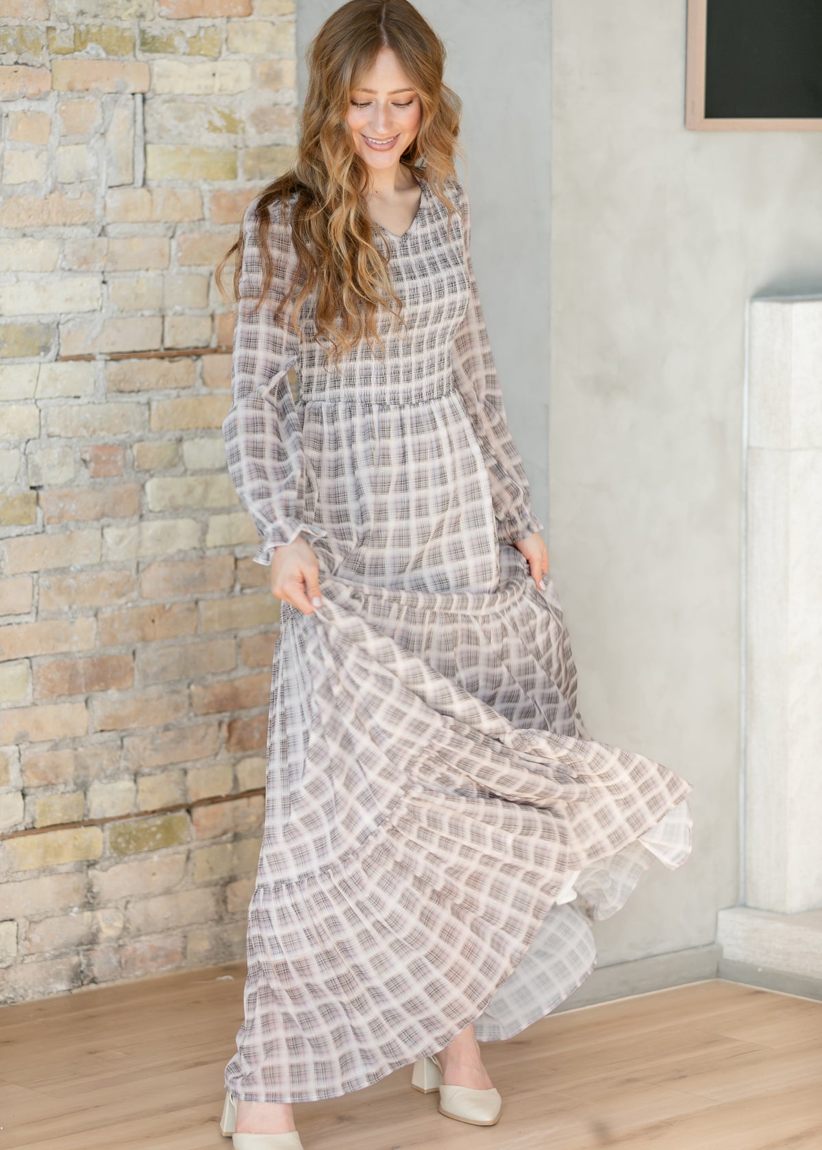 Taupe plaid maxi dress twirling to show the tiered, floor-length skirt in motion.