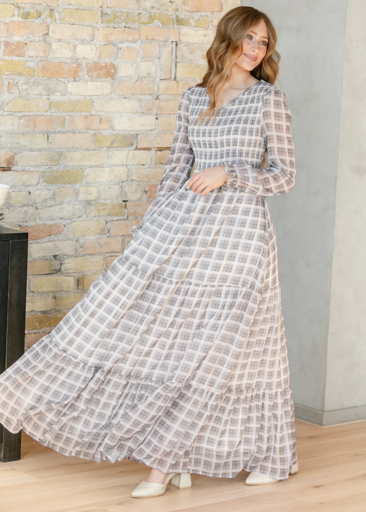 Taupe plaid maxi dress with a tiered skirt, styled against a concrete pillar with ivory block heels.