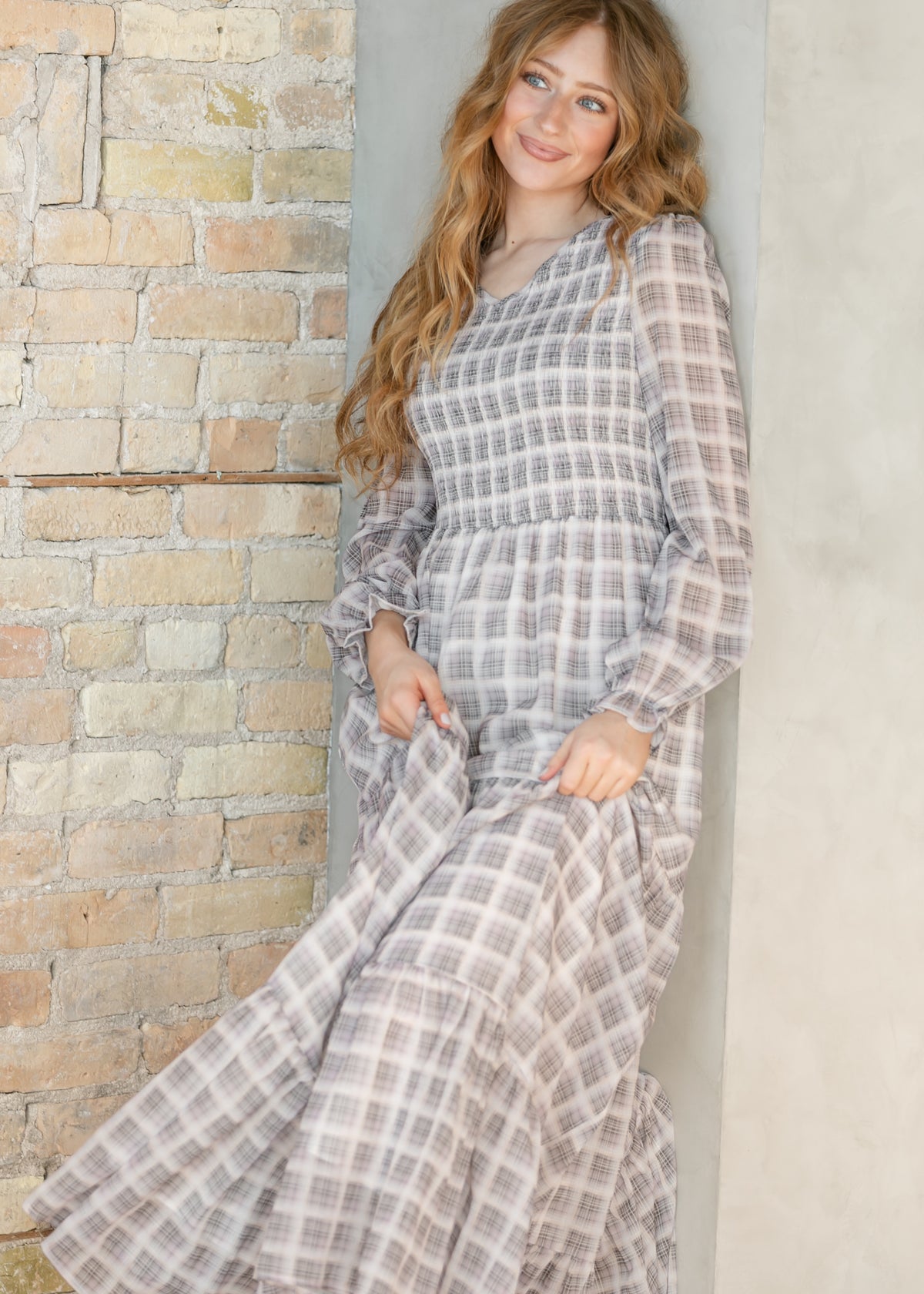 Close-up of the smocked V-neckline and ruffled cuff detail on the taupe plaid maxi dress.