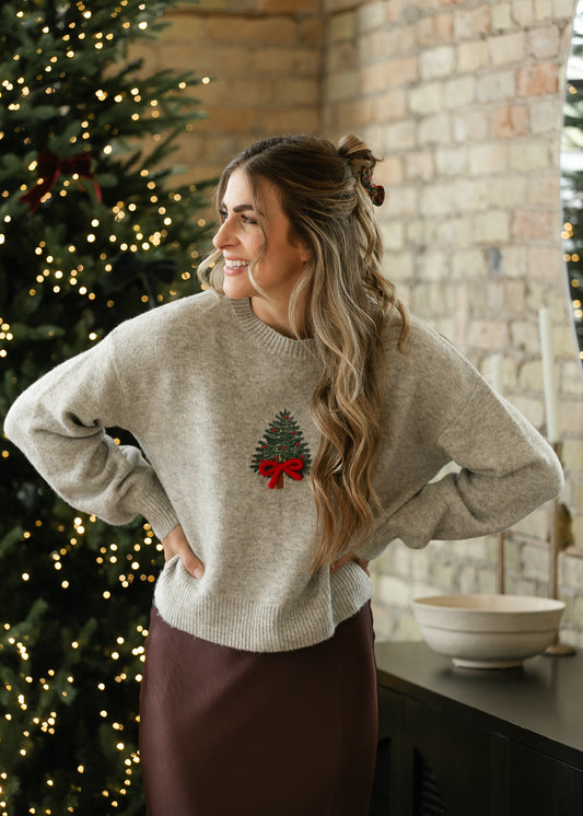 Heather gray embroidered Christmas sweater paired with a brown satin skirt and black ankle-strap heels.