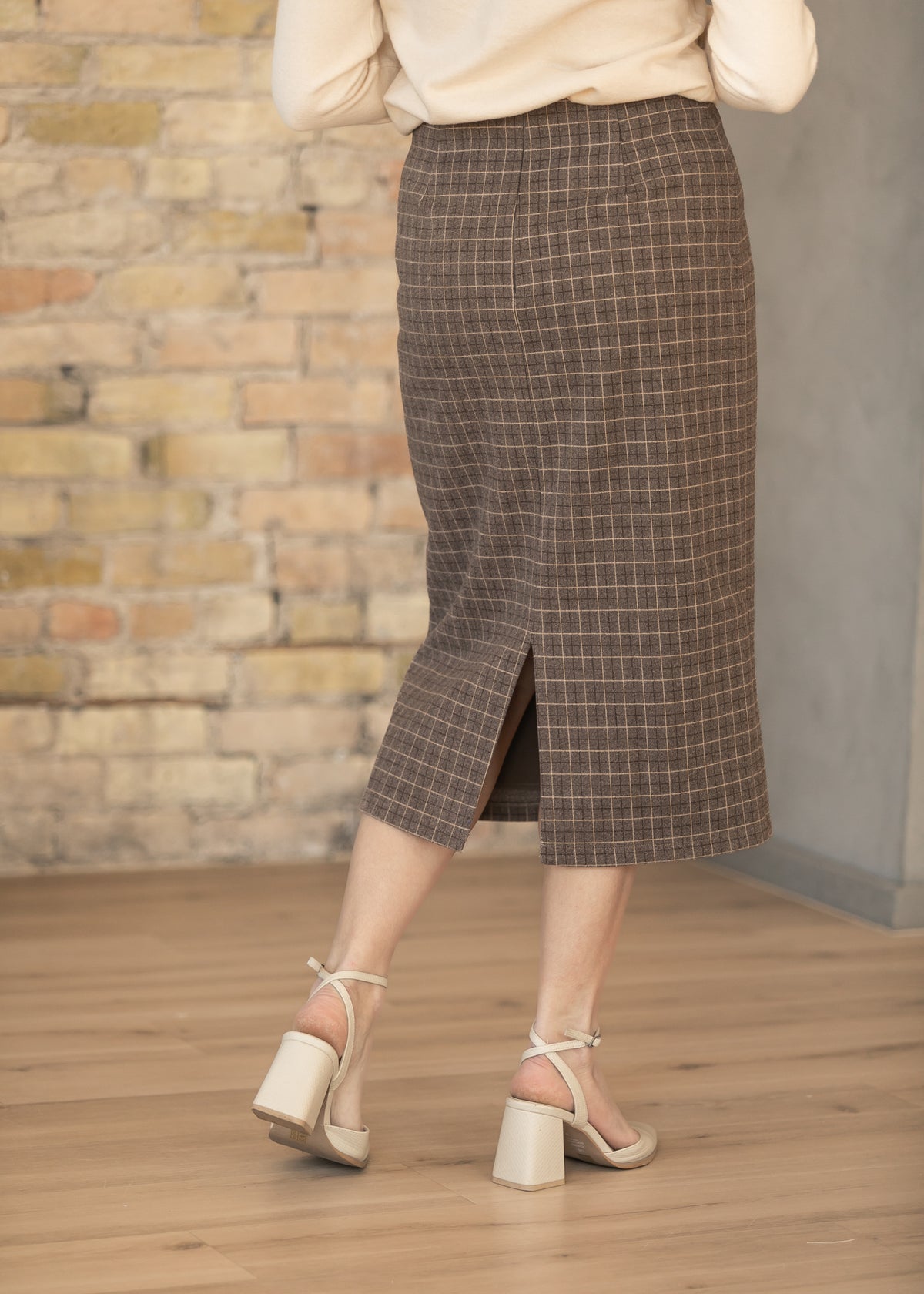 Back of brown plaid midi pencil skirt showing center back slit and tailored fit.