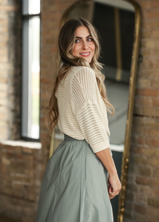 Cream short sleeve crochet cardigan with open knit texture and ribbed trim, styled with a sage maxi skirt.