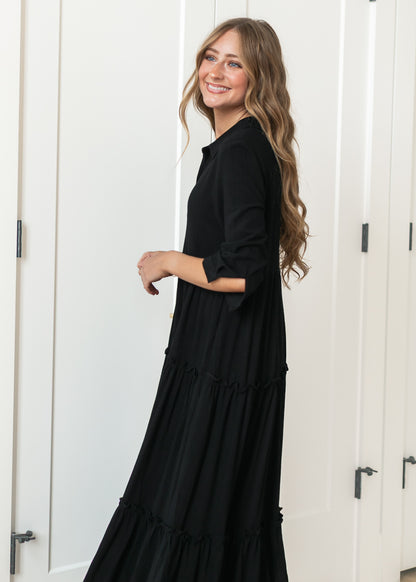 Black Elsie dress from the side showing the A-line silhouette and tiered midi skirt.