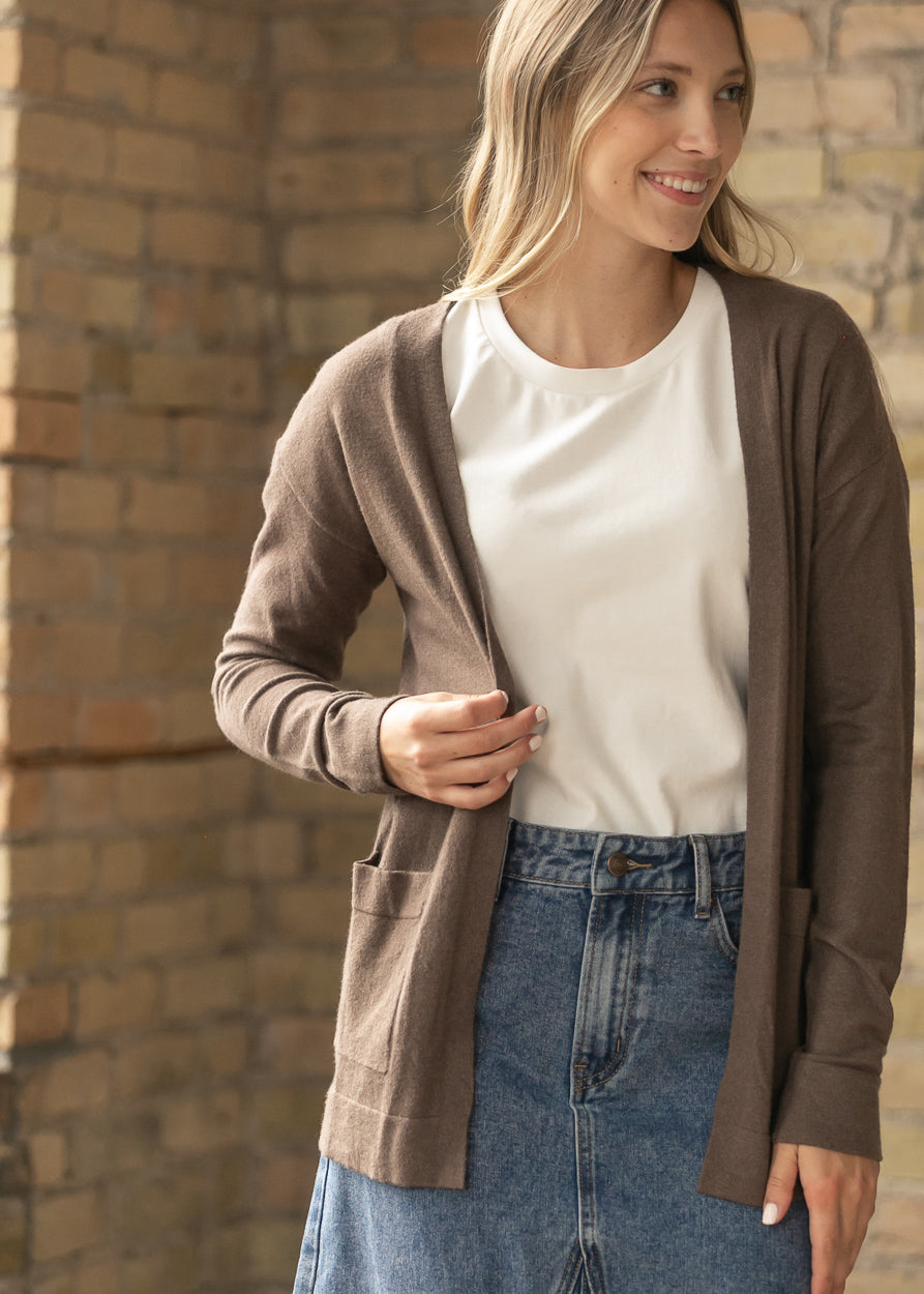 Front view of the coffee short cardigan open over a cream tee and denim midi skirt.