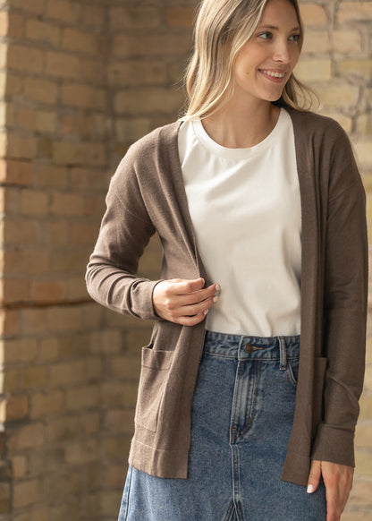 Front view of the coffee short cardigan open over a cream tee and denim midi skirt.
