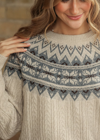 Close-up of cream Fair Isle knit sweater showing patterned neckline and cable knit texture