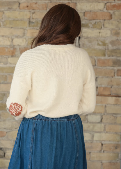 Back view of cream floral knit sweater styled with a blue denim skirt