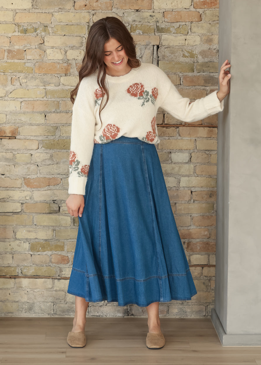 Full-length front view of cream floral sweater with a blue denim midi skirt