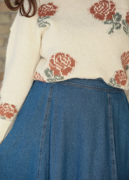 Close-up of cream floral sweater hem styled with a blue denim skirt