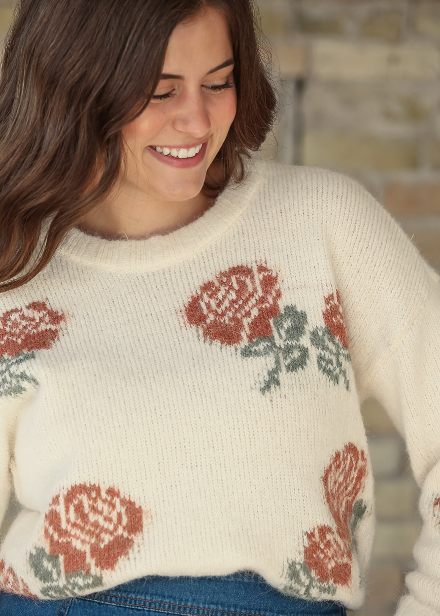 Close-up of cream floral sweater hem styled with a blue denim skirt