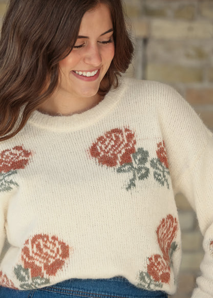 Close-up of cream floral sweater hem styled with a blue denim skirt