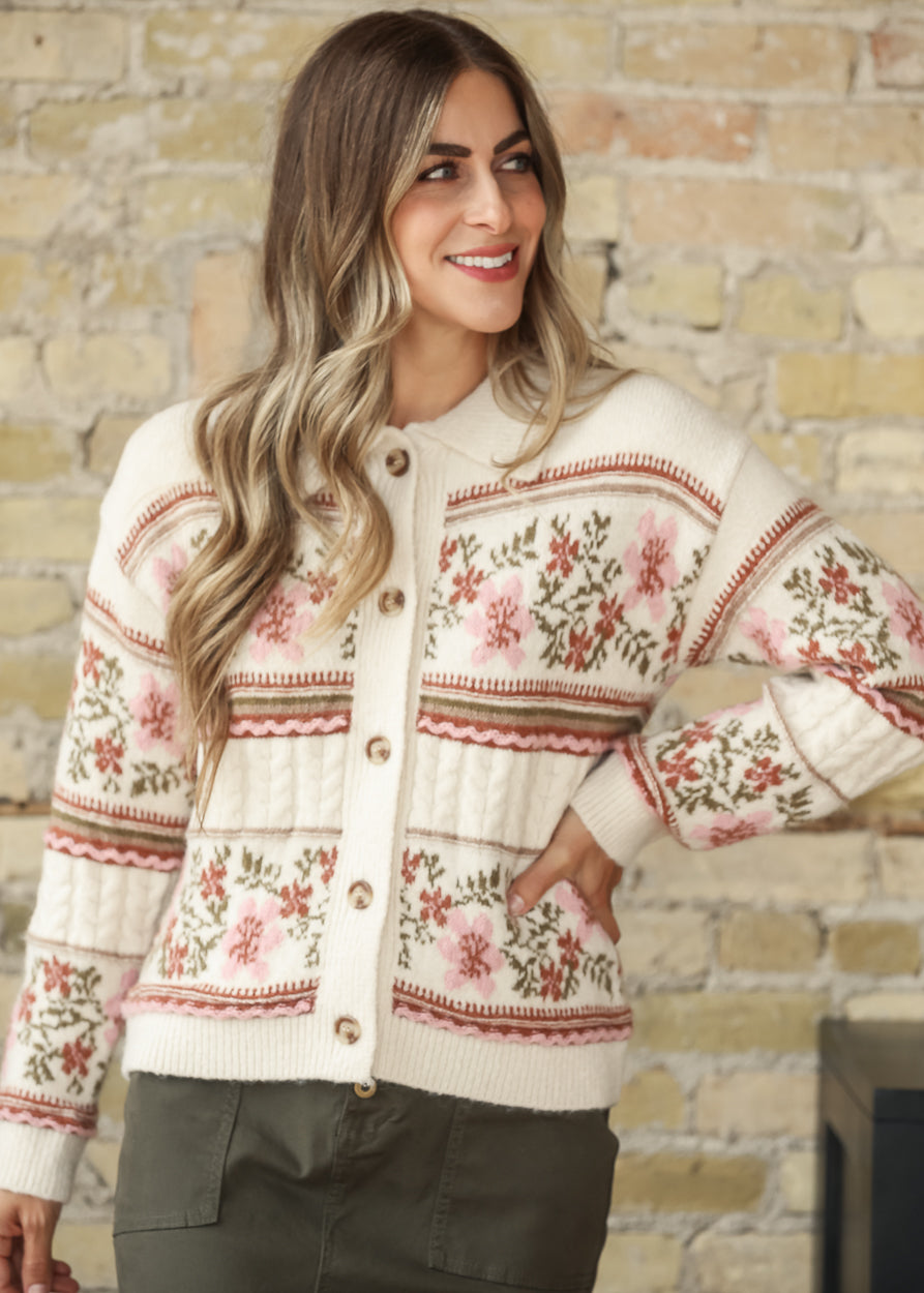Model wearing a cream floral button-front cardigan with olive skirt, angled front view