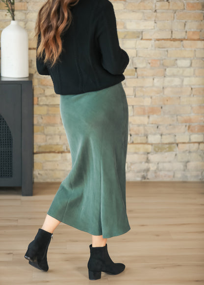 Back angled view of emerald faux suede midi skirt with black sweater and ankle boots