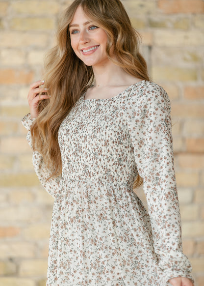 Close-up of a woman wearing a floral dress against a brick wall.