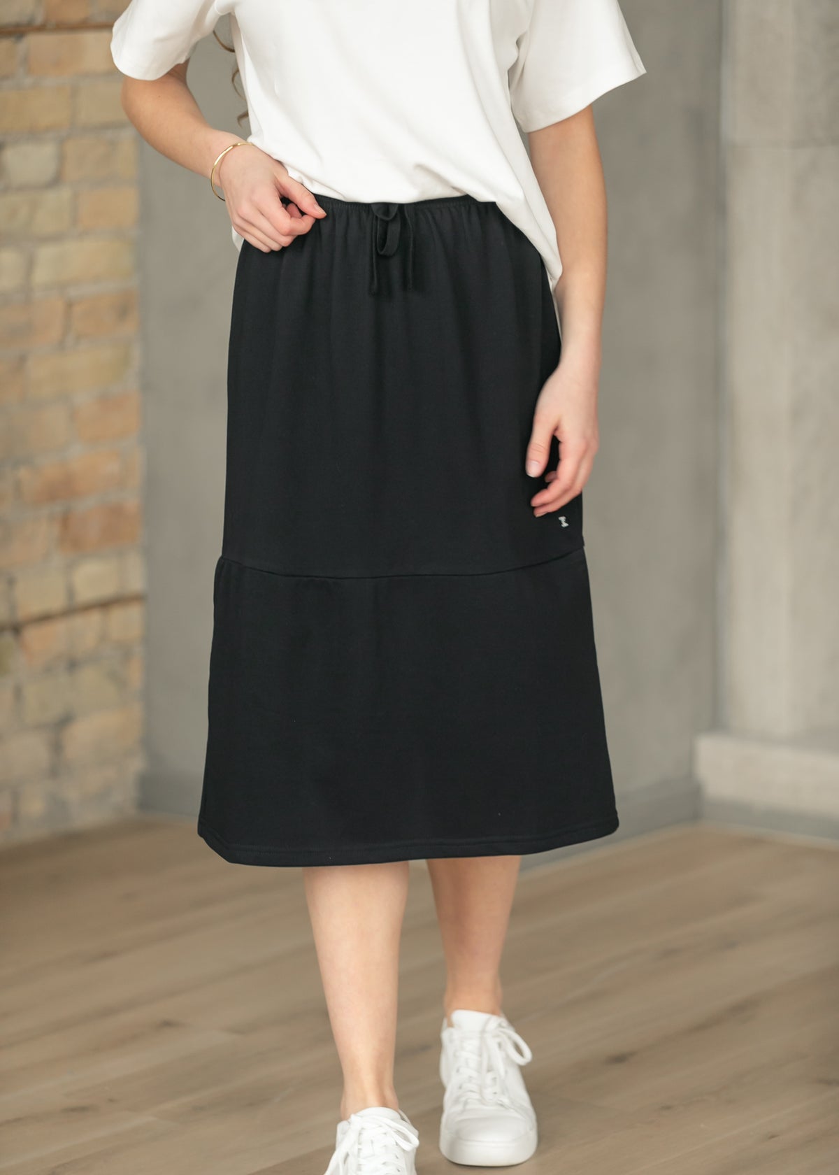 Black Gracie midi sweat skirt with side pocket and drawstring waist, styled with a white tee.
