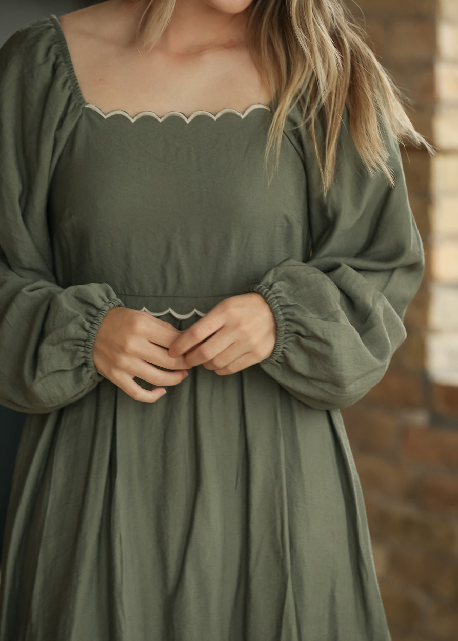 Close-up of winter sage dress showing square neckline, scalloped ivory trim, and elastic-cuff sleeves.