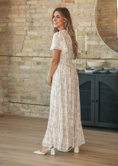 Cream floral maxi dress styled with ivory block heels, side view showing the flutter sleeves.