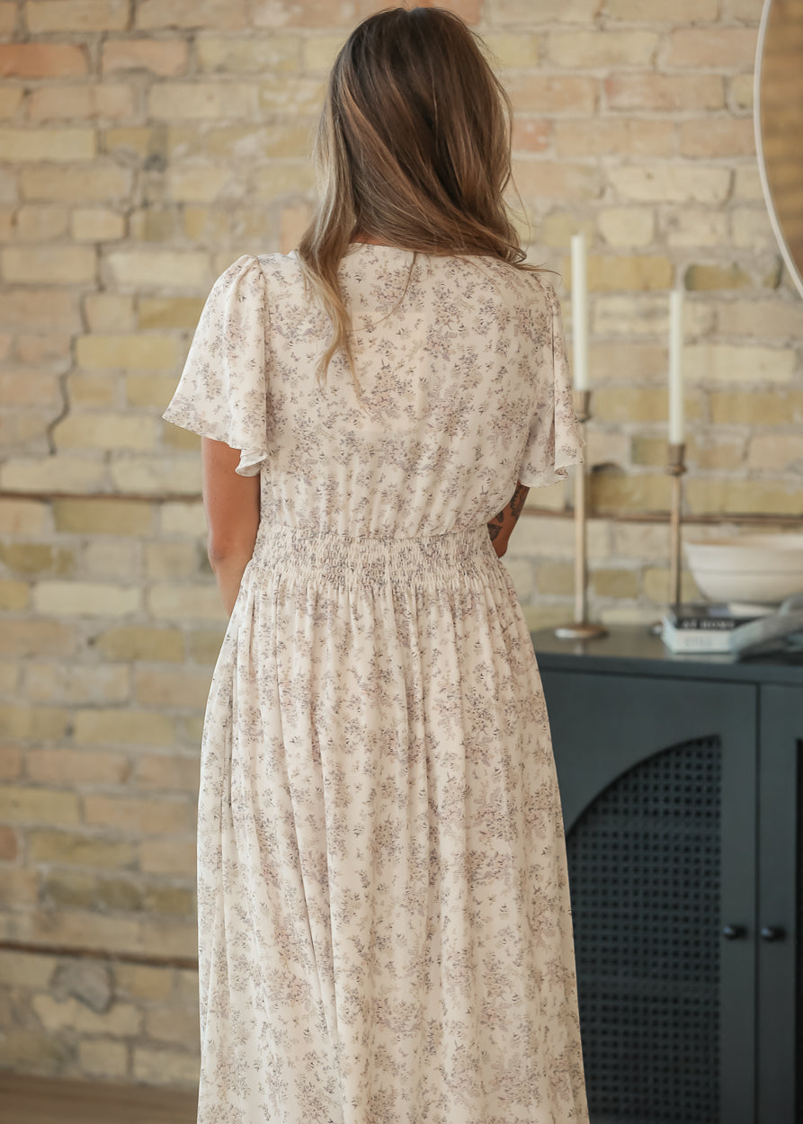 Back of the cream floral maxi dress showing the smocked waist and flutter sleeve detail.