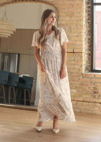 Floral maxi dress skirt in motion, showing the ruffled hem and flowing silhouette by a sunlit window.