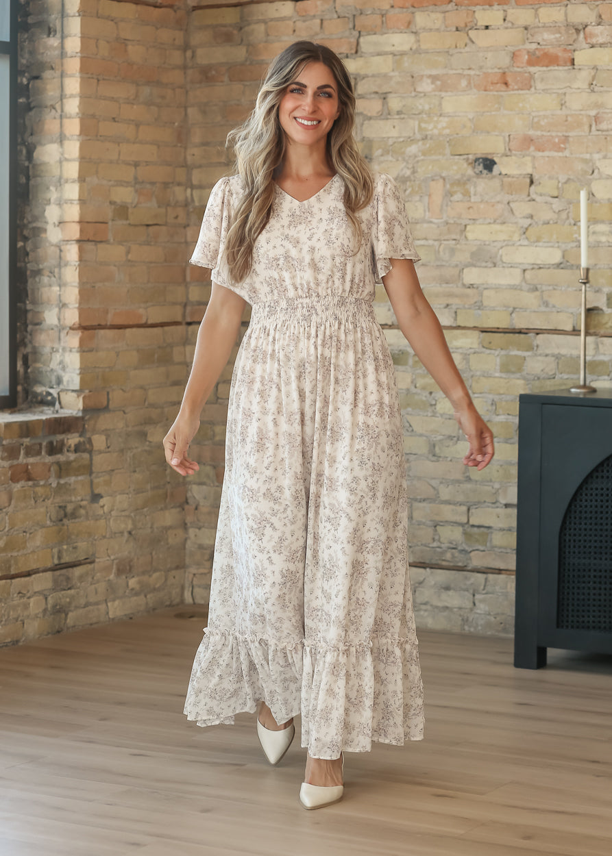 Floral maxi dress skirt in motion, showing the ruffled hem and flowing silhouette by a sunlit window.